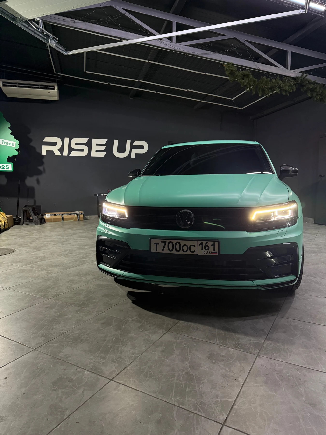 Зелёный автомобиль у стены с надписью Rise UP
